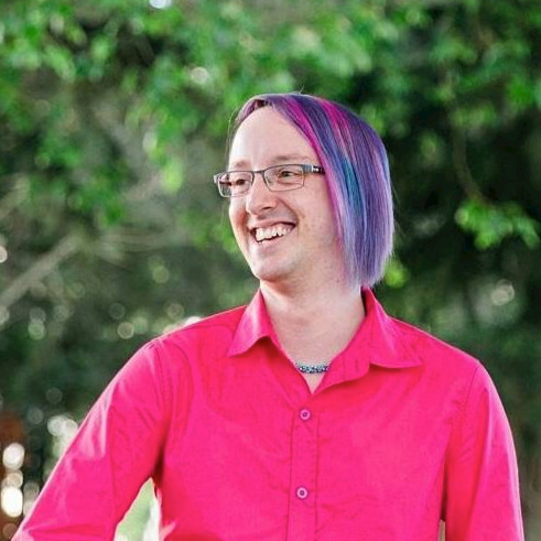 a man with purple hair and glasses smiling